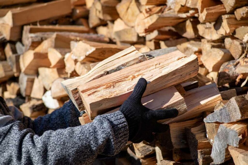 Man taking dry split firewood from stack for heating house