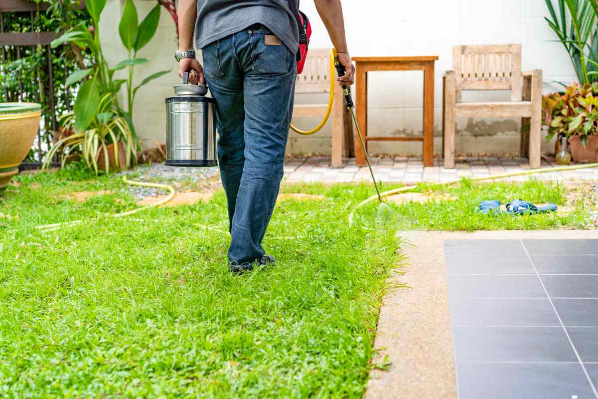 Termite control technician working in yard spraying insecticide. 
