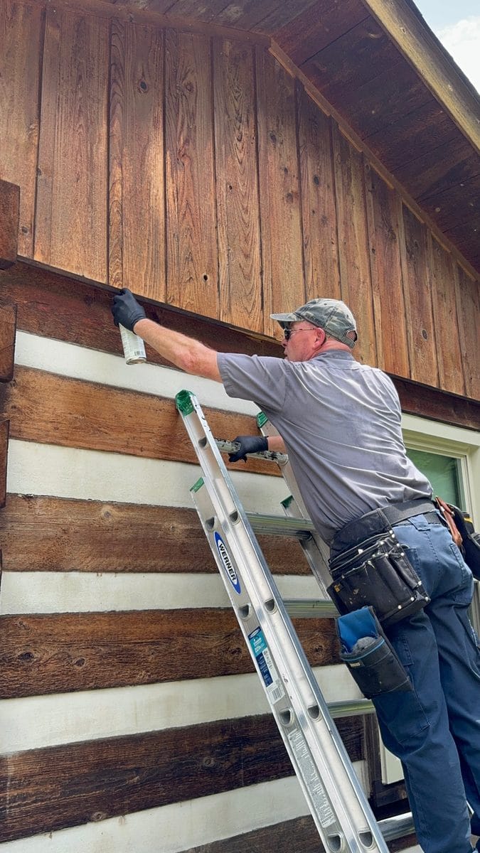 Clegg's Pest Control technician on a ladder treating and filling carpenter bee holes in the wooden siding of a North Carolina home
